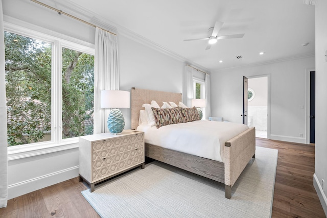 bedroom with connected bathroom, hardwood / wood-style flooring, ceiling fan, and ornamental molding