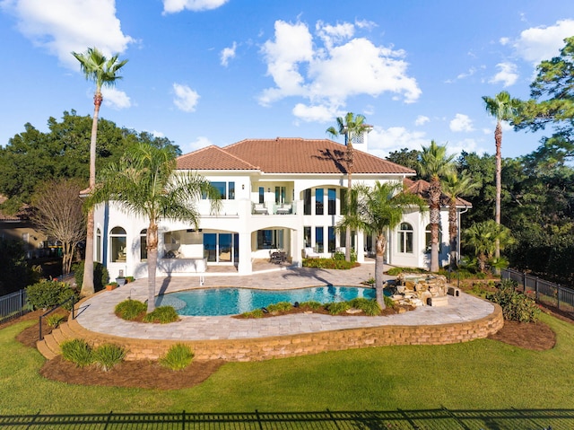 rear view of house with a fenced in pool, a patio area, a balcony, and a lawn