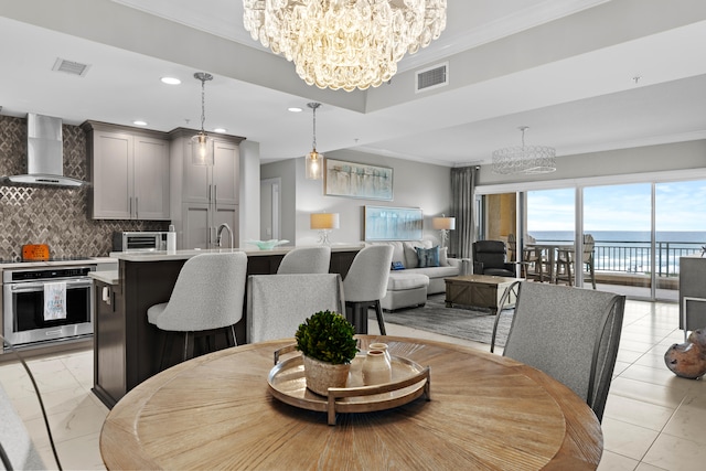 dining room with a water view, ornamental molding, and a notable chandelier