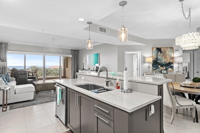 kitchen with light stone counters, ornamental molding, sink, pendant lighting, and an island with sink