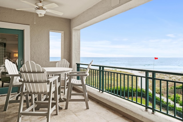 balcony with ceiling fan, a water view, and a view of the beach