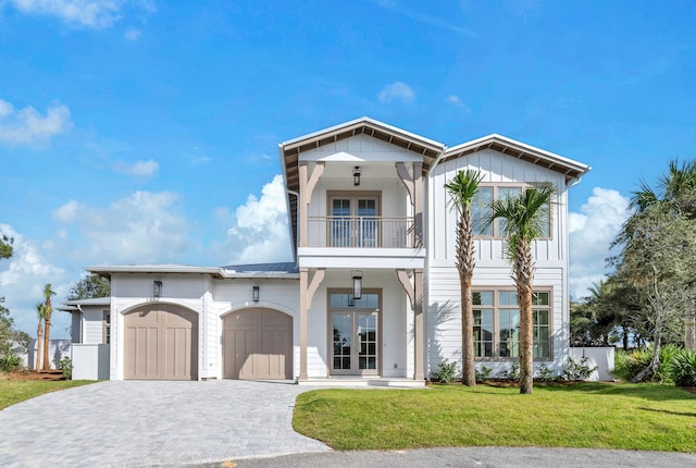 view of front of property with french doors, a balcony, a garage, and a front lawn