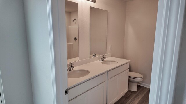 bathroom featuring toilet, a shower, hardwood / wood-style flooring, and vanity