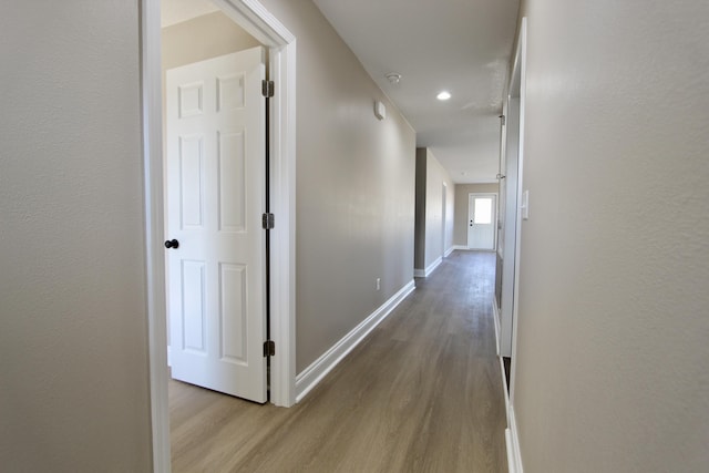 corridor featuring wood finished floors and baseboards