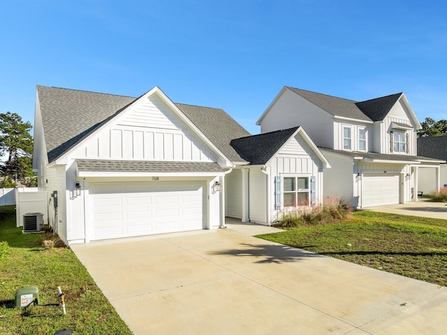 view of front of house featuring a front yard, a garage, and central AC unit