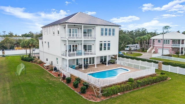 back of house with a yard, ceiling fan, a balcony, and a fenced in pool