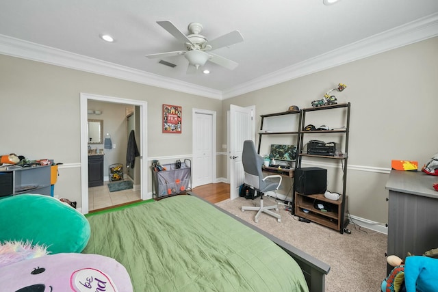 carpeted bedroom featuring a closet, connected bathroom, ceiling fan, and crown molding