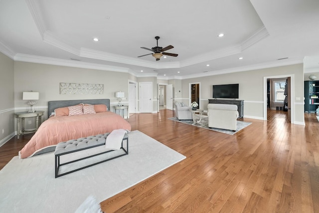 bedroom featuring wood-type flooring, a raised ceiling, ceiling fan, and crown molding