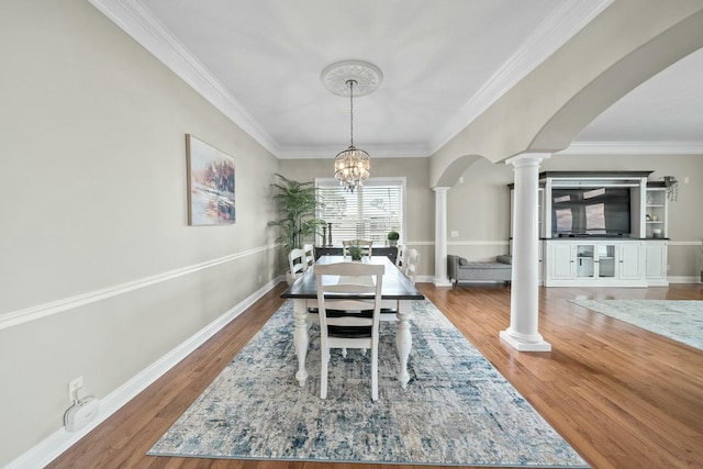 dining room featuring decorative columns, a chandelier, crown molding, and wood-type flooring