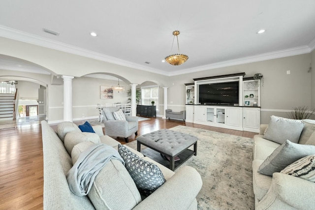 living room with a healthy amount of sunlight, ornate columns, ornamental molding, and light hardwood / wood-style flooring