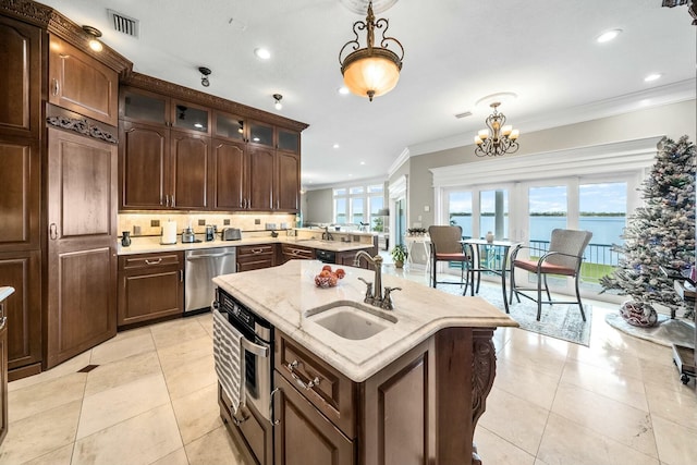 kitchen featuring dishwasher, a water view, sink, hanging light fixtures, and decorative backsplash