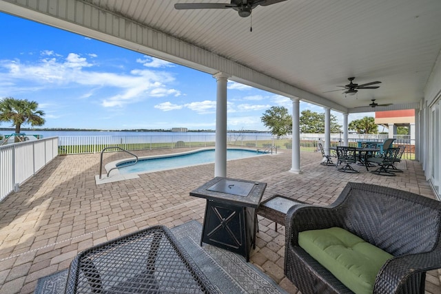 view of patio with a fenced in pool, ceiling fan, and a water view