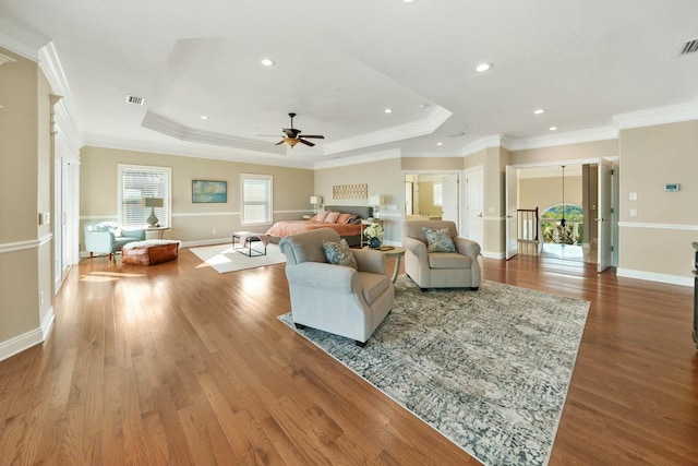 living room with a tray ceiling, crown molding, hardwood / wood-style floors, and ceiling fan