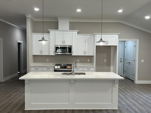 kitchen with appliances with stainless steel finishes, white cabinetry, sink, hanging light fixtures, and a center island with sink