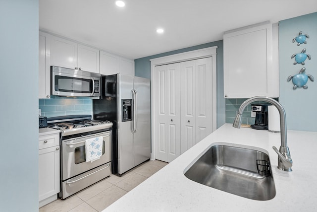kitchen featuring sink, light tile patterned floors, tasteful backsplash, white cabinets, and appliances with stainless steel finishes