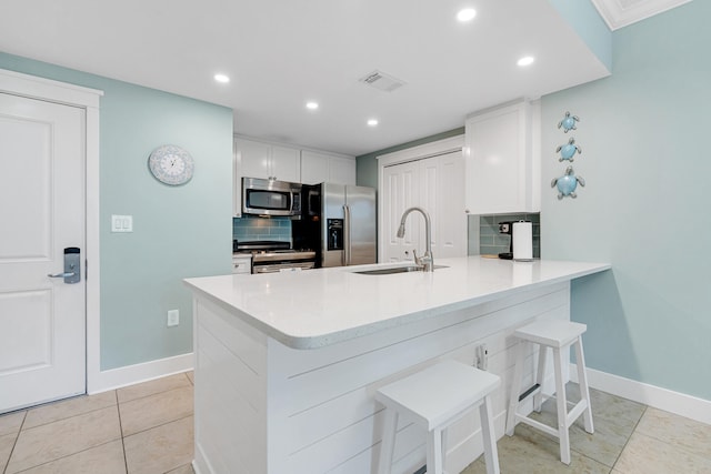 kitchen featuring sink, appliances with stainless steel finishes, tasteful backsplash, kitchen peninsula, and a breakfast bar area