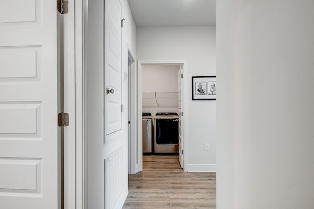 corridor with light wood-type flooring and washing machine and clothes dryer