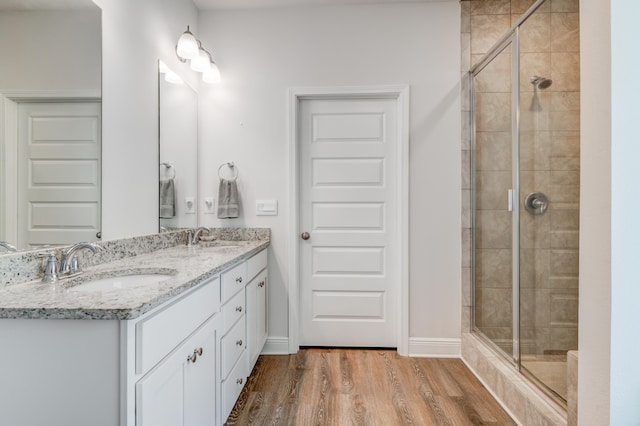 bathroom featuring hardwood / wood-style floors, vanity, and a shower with door