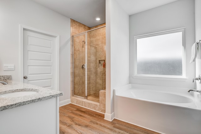 bathroom with plus walk in shower, vanity, and hardwood / wood-style flooring