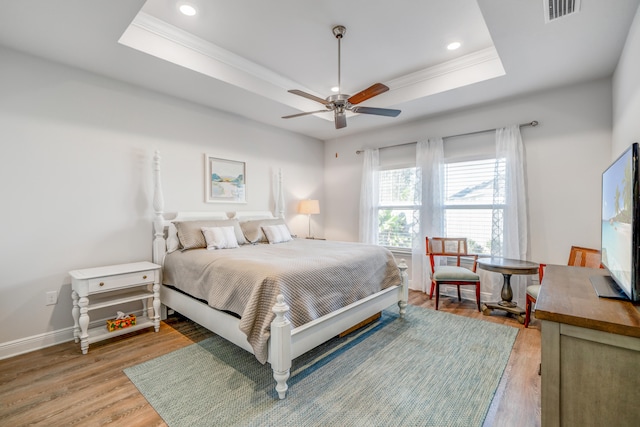 bedroom with a raised ceiling, ceiling fan, hardwood / wood-style floors, and crown molding