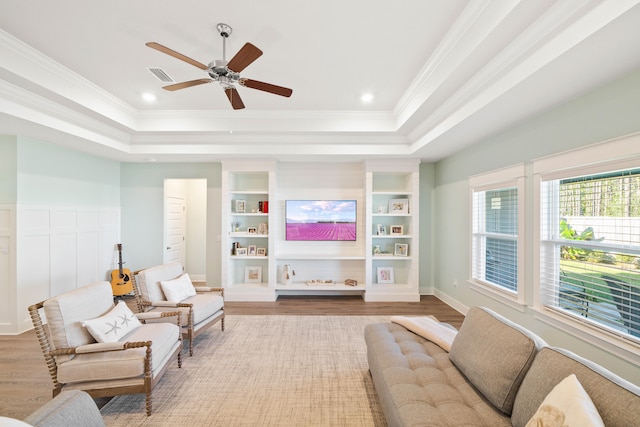 living room with a raised ceiling, ceiling fan, hardwood / wood-style floors, and ornamental molding