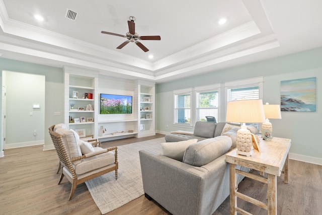 living room with a tray ceiling, ceiling fan, crown molding, and light hardwood / wood-style floors