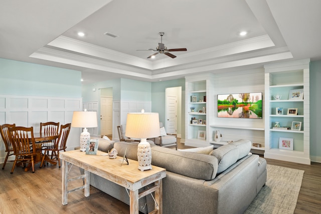 living room with a raised ceiling, ceiling fan, crown molding, and hardwood / wood-style flooring