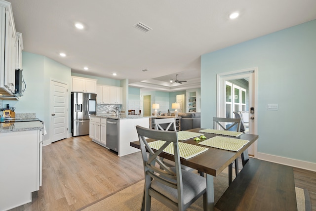 dining room with light hardwood / wood-style floors, ceiling fan, and sink