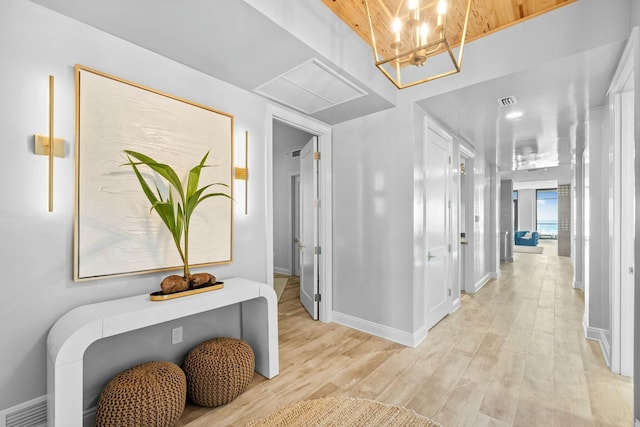 hall with a chandelier and light wood-type flooring