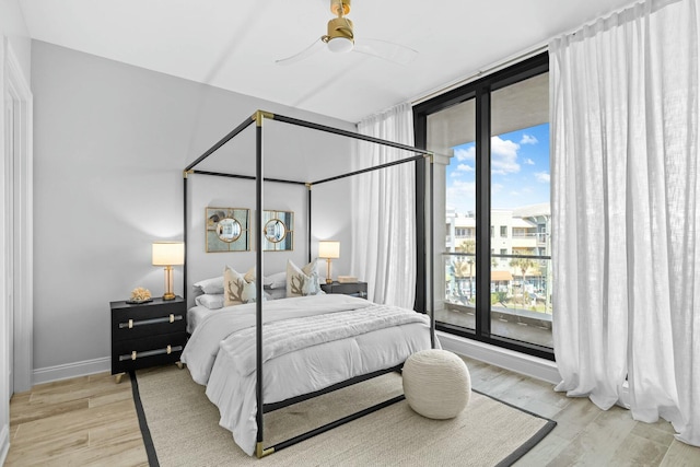 bedroom featuring expansive windows, light hardwood / wood-style floors, multiple windows, and ceiling fan