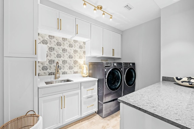 washroom featuring washing machine and clothes dryer, light hardwood / wood-style flooring, cabinets, and sink