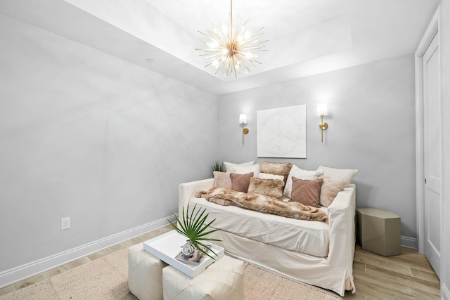 bedroom featuring a raised ceiling, a chandelier, and light wood-type flooring