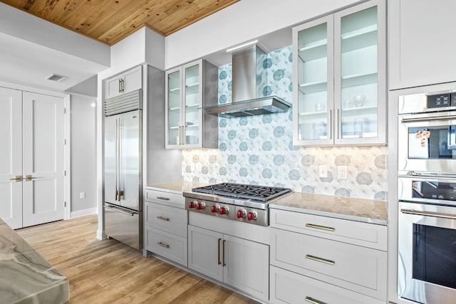 kitchen featuring light wood-type flooring, wall chimney range hood, appliances with stainless steel finishes, and wooden ceiling