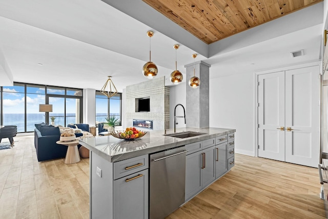 kitchen with sink, hanging light fixtures, stainless steel dishwasher, a water view, and light wood-type flooring