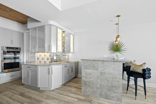 kitchen featuring pendant lighting, light wood-type flooring, gray cabinets, and double oven