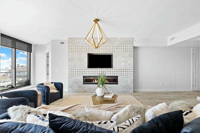 living room featuring light wood-type flooring, a tile fireplace, and a chandelier