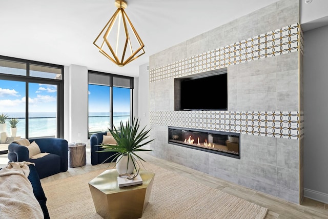 living room with a tiled fireplace, light hardwood / wood-style flooring, and a wall of windows