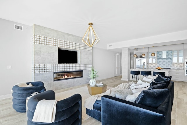 living room with light wood-type flooring, sink, and a tiled fireplace