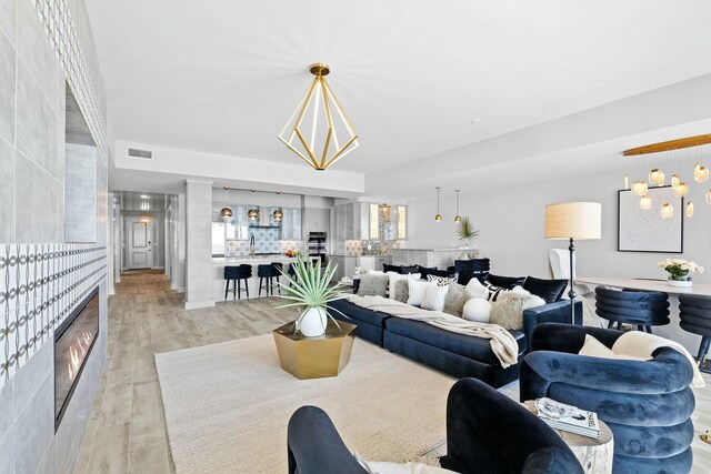 living room with an inviting chandelier, sink, and light hardwood / wood-style flooring