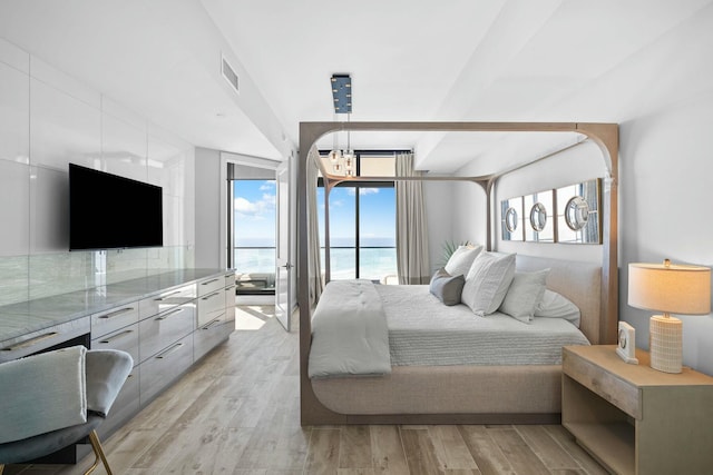 bedroom with access to exterior, light hardwood / wood-style flooring, and an inviting chandelier