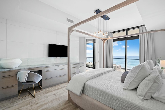 bedroom with access to outside, a chandelier, built in desk, and light wood-type flooring