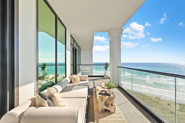 balcony featuring outdoor lounge area, a water view, and a beach view