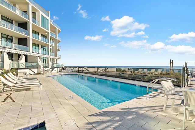 view of swimming pool featuring a patio area and a water view