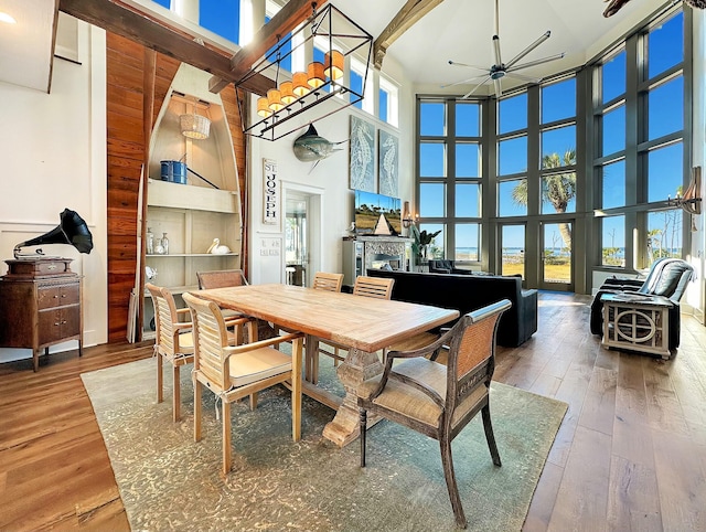 dining area with hardwood / wood-style flooring, a healthy amount of sunlight, and a high ceiling