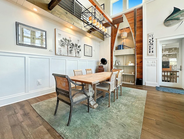 dining area featuring a high ceiling, dark hardwood / wood-style floors, and beam ceiling