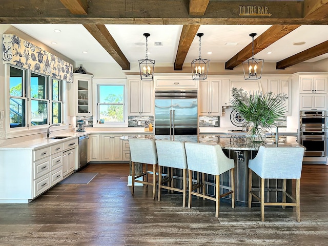 kitchen with beam ceiling, a center island, dark wood-type flooring, decorative backsplash, and appliances with stainless steel finishes