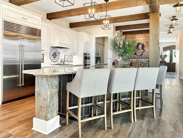 kitchen featuring dark hardwood / wood-style flooring, stainless steel appliances, white cabinetry, and an island with sink