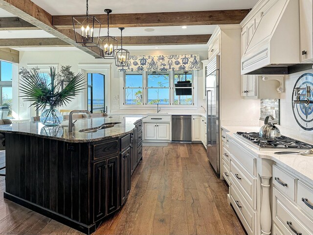 kitchen with beam ceiling, white cabinetry, a healthy amount of sunlight, and light stone countertops