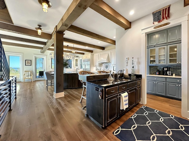 kitchen featuring a kitchen bar, backsplash, sink, beam ceiling, and dark hardwood / wood-style floors