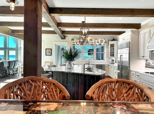 kitchen with white cabinets, a center island, light stone counters, and stainless steel appliances